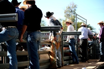 Bull riders stand behind the shoots and prepare themselves for their next ride. Others help the upcoming bull rider on his bull and keep him safe. (Naomi Klocmann/Borderzine.com)
