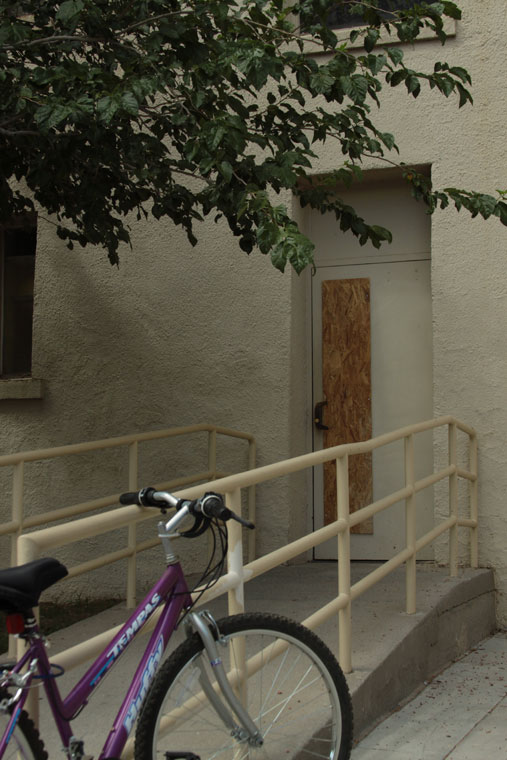 Puerta de ingreso a Bell Hall. La placa vertical de madera reemplaza al vidrio que fuera impactado por la bala antes de incrustarse en la oficina 111. (Raymundo Aguirre/Borderzine.com)