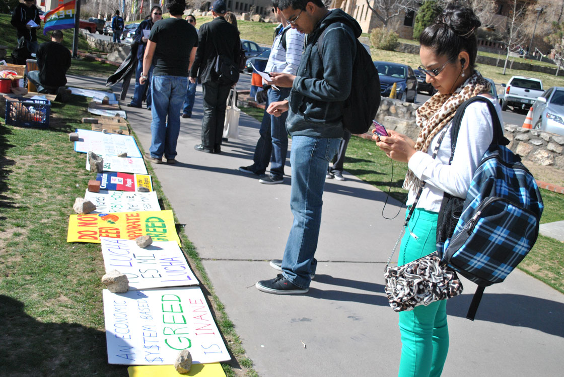 Protest signs and books call students' attention at Leech Grove on the UTEP campus. (Lourdes Marie Ortiz/Borderzine.com)