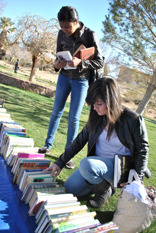 Neyma Gonzalez (standing up), freshman engineering major, and Andrea Caraveo, freshman forensic science major, look at books to buy at the Occupy El Paso book sale. (Lourdes Marie Ortiz/Borderzine.com)