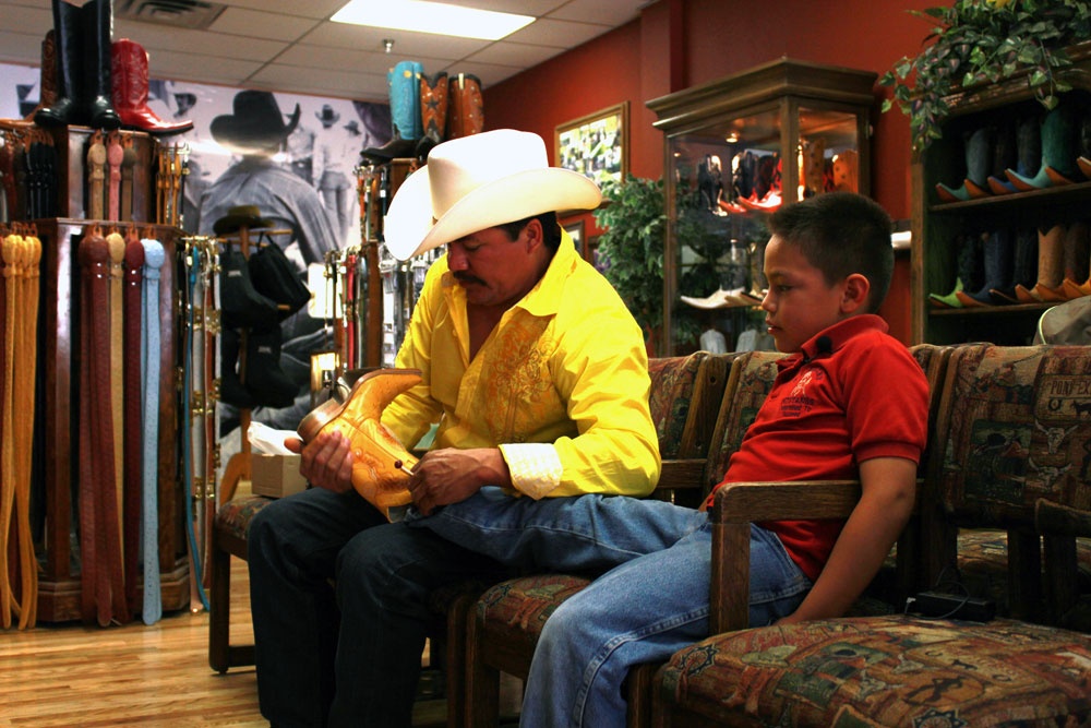 Ricardo Arellano helps out his 8 year-old son trying new boots at Juarez Boots. (Adolfo Mora/Borderzine.com)