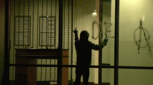 A member of the 915 Anarchy group paints graffiti at the downtown branch of Bank of America. (Alejandro Alba/Borderzine.com)