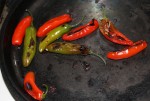 Roasting serranos for the salsa on a comal. (Cheryl Howard/Borderzine.com)