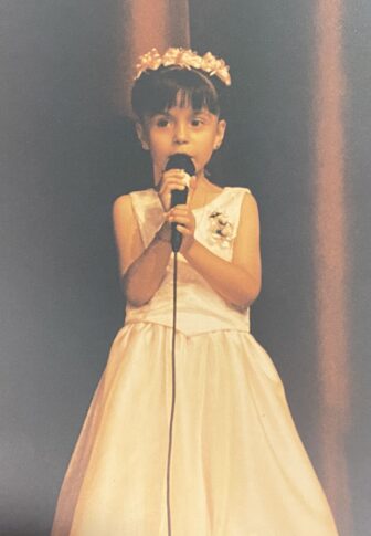 Stephanie Chavez holding a microphone as she gives her last speech kindergarten in graduation May 2003