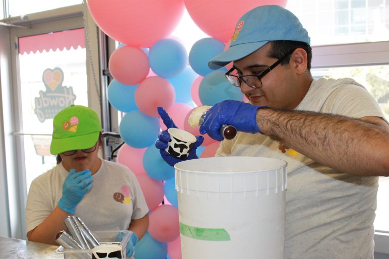 Howdy Homemade ice cream employees Andrea Ortega, left, and Stephen Vasquez, right, scoop birthday cake ice cream into containers at their ice cream factory on Nov. 1, 2022.