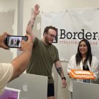 Brandy Ruiz, center, holds a sheet cake while another classmate pretends he is going to slap it out of her hands. Another classmate is watching and another is filming on a smart phone.