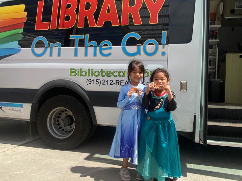 Little girls standing in front of the El Paso BookMobile after getting their new library cards dress as Elsa and Anna from the movie Frozen.